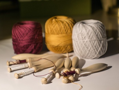 Narzędzia do koronki klockowej - klocki i trzy szpule nici: biała, żółta i bordowa.