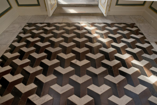 Fragment posadzki w Bibliotece Króla. Jest to układ elementów w dwóch kolorach jasnego i brązowego kamienia.