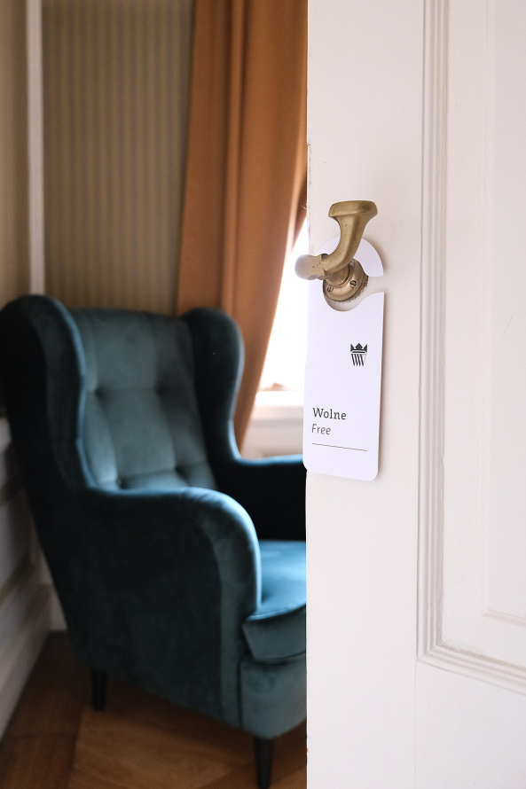 Zdjęcie przedstawia pokój z fotelem. Na klamce drzwi wisi tabliczka "wolne / free".